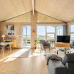 Living and dining area with wooden ceiling, large windows, and view of the landscape.