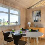 Round dining table with black chairs and green cups. Wooden walls and large window with view.