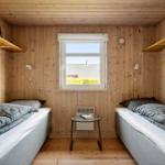 Two single beds in a wooden room with window and small table.