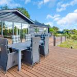 Deck with table and chairs, view of lawn and sea.