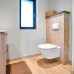 Bathroom with toilet, sink and shower. Wood look and window.
