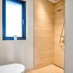 Bathroom with shower, toilet, and window with blue frame.
