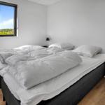 Bedroom with large bed, window overlooking green areas, and two nightstands with lamps.