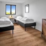 Two single beds, wooden floor, window with view, dresser and wall mirror.