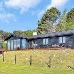 Modern log cabin with terrace and garden. View of forest and sky.