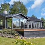 Modern wooden cabin with terrace and large glass area in the green.