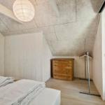 Schlafzimmer mit Bett, Schrank und Kleiderständer unter schrägem Dach