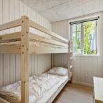 Zimmer mit Doppelstockbett, Fenster und Kleiderhaken an der Wand.