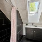 Badezimmer mit Dusche, Waschbecken und Dachfenster.