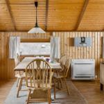 Esszimmer mit Holztisch, Stühlen und Sofa. Holzwände, Decke und Boden.