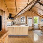 Küche mit Essbereich und Holzdecke. Fernseher, Kühlschrank und Tisch mit Stühlen.