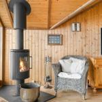Wohnraum mit Holzwand, Kaminofen, Sessel und Fernseher