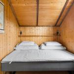 Ein Bett mit Matratze und Kissen in einem holzverkleideten Raum mit Fenster und Wandposter.
