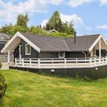 Ein Haus mit dunklem Holz und weißer Veranda im Grünen.
