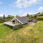 Haus mit Terrasse und Garten, umgeben von grüner Landschaft und Hecken.