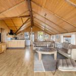 Wohnbereich mit Sofa, Esstisch und Küchenzeile unter Holzdecke.