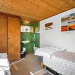 Zimmer mit zwei Betten, Holzdecke und integriertem Bad mit grüner Fliesenwand.