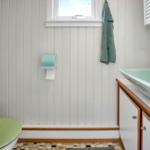 Badezimmer mit grünem Waschbecken, Toilette und grüner Handtuchhaken.