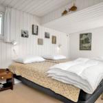 Schlafzimmer mit Doppelbett, weißen Wänden und Fenstern mit Vorhängen.