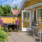 Terrasse mit Tisch, Stühlen und Sitzgelegenheit vor gelbem Haus