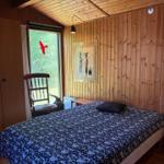 Schlafzimmer mit Holzwand, Bett, Stuhl und Fenster.