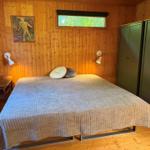 Schlafzimmer mit Holzwand, Bett, Kleiderschränken und Fenster.