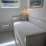 Ein Schlafzimmer mit weißer Matratze, Wandbild und Fenster mit Blick nach draußen.