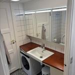 Badezimmer mit Waschmaschine, Spiegel und Toilette