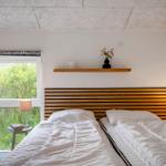 Zimmer mit Doppelbett, Holzkopfteil, Fenster und Nachttisch mit Lampe.
