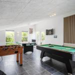 Raum mit Billardtisch, Tischfußball und Dartscheibe. Fenster mit Blick auf Grün.