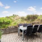 Terrasse mit Tisch und Stühlen, Grill und Blick auf Grünflächen.