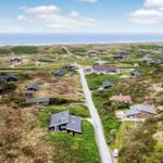 Aerial view of coastal village with houses, dunes, and ocean in background.