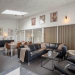 Wohn- und Essbereich mit Ledersofa, Fernseher und Wandbildern.