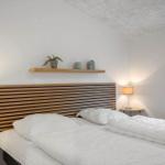 Schlafzimmer mit Doppelbett, Holzkopfteil und Nachttischen mit Lampen.