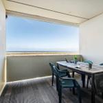 Terrasse mit Tisch und Stühlen, Blick auf Strand und Meer.