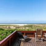Terrasse mit Liege und Stühlen bietet Blick auf Strand und Dünen.