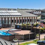 Poolbereich mit Rutsche und Spielplatz vor Wohngebäuden.