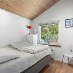 Schlafzimmer mit Bett, Fenster und Stuhl. Holzdecke und weißer Schrank.