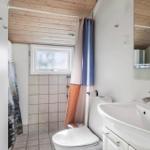 Badezimmer mit Toilette, Waschbecken und Dusche mit Fenster