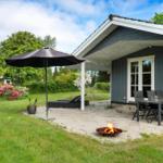 Hütte mit Terrasse, Sitzgruppe, Sonnenschirm und brennendem Feuerkorb im Garten.