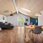 Wohn- und Essbereich mit Holzdecke, Tisch, Stühlen und Sofa.