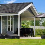 Haus mit Terrasse, Sitzgelegenheiten und Sonnenschirm. Grünflächen und Blumen im Vordergrund.