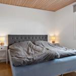 Bedroom with bed, nightstands, and window. Wooden ceiling and white walls.