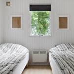Two beds with striped bedding in a room with white paneling and window overlooking trees.