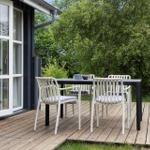 Deck with table and chairs in front of a house with glass doors.