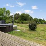 High-quality hot tub on wooden terrace with grill and seating area in the green.