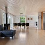 Living and dining area with wooden ceiling, sofa, dining table, and fireplace.