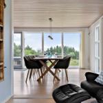 Dining room with table, chairs, and view of forest. Black leather recliners in foreground.