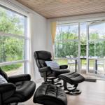 Two black recliners with cushions are by large windows. Through the glass door, a terrace with garden is visible.