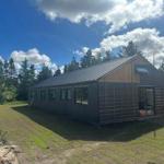 Moderne Holzhütte mit großem Fenster und Terrasse im Wald